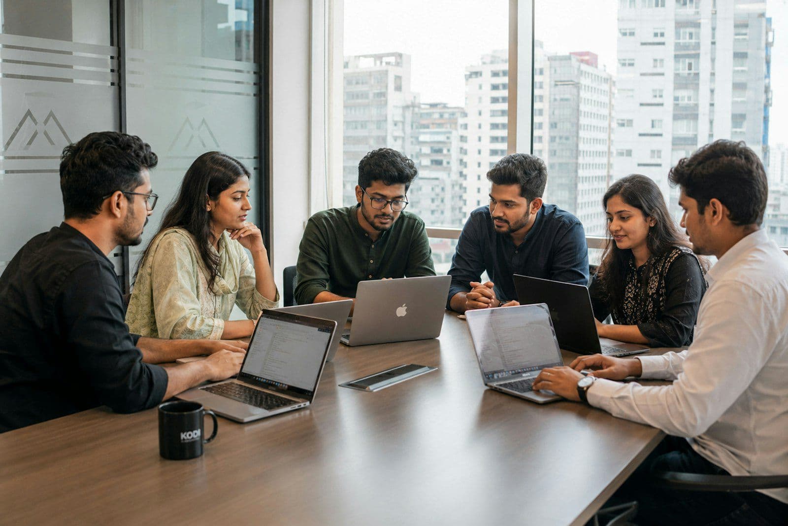 Team meeting around a table with laptops